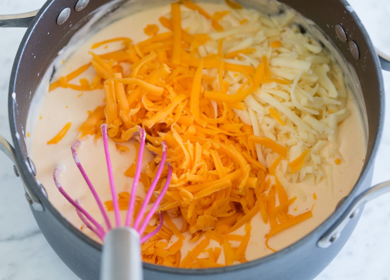 Mac and Cheese whisking together a mac and cheese sauce