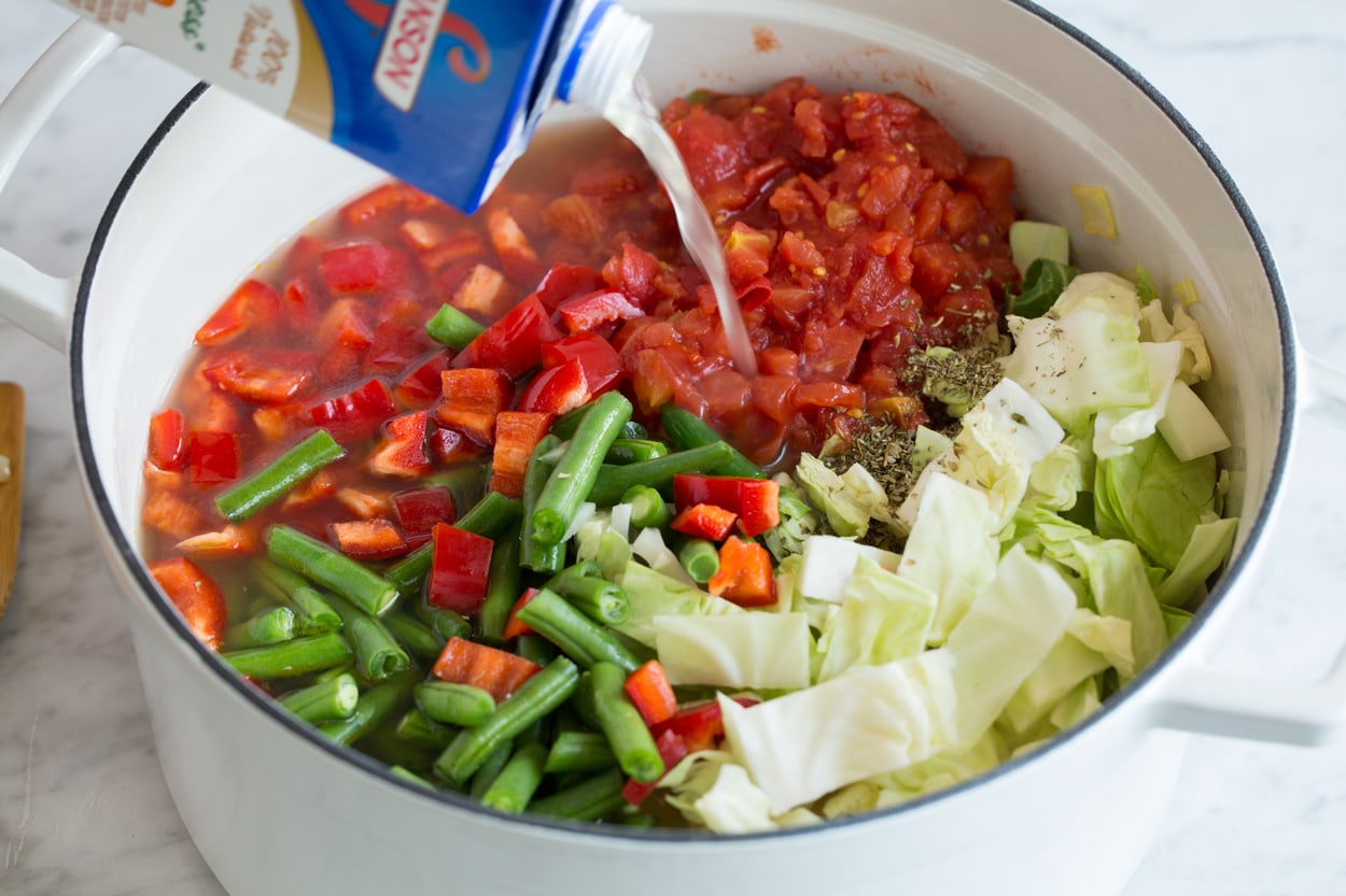 Cabbage Soup Adding cabbage, tomatoes, green beans, chicken broth and seasoning to soup mixture.