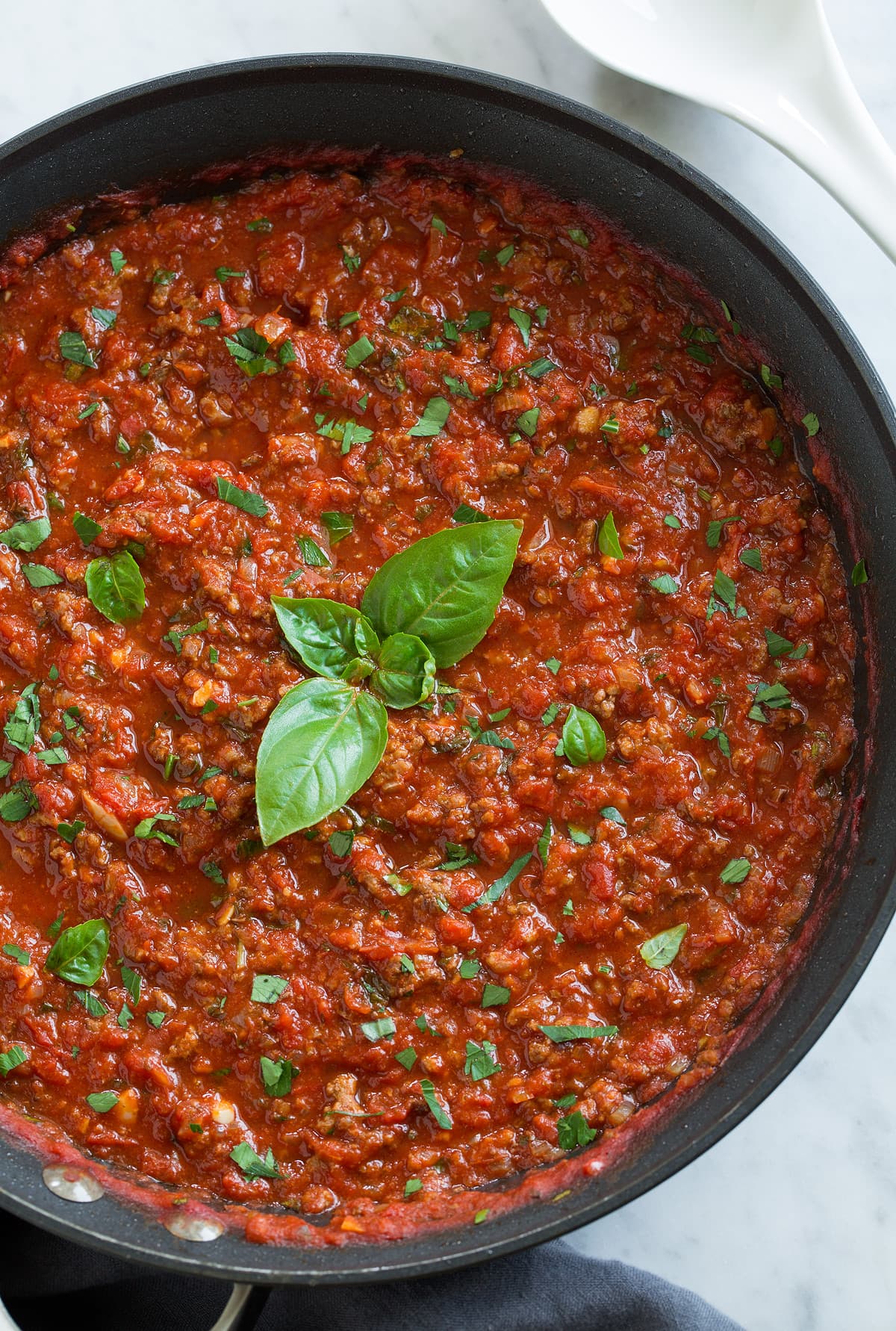Homemade Spaghetti Sauce Overhead close up image of the best spaghetti sauce from scratch in a skillet with basil leaves in the center.