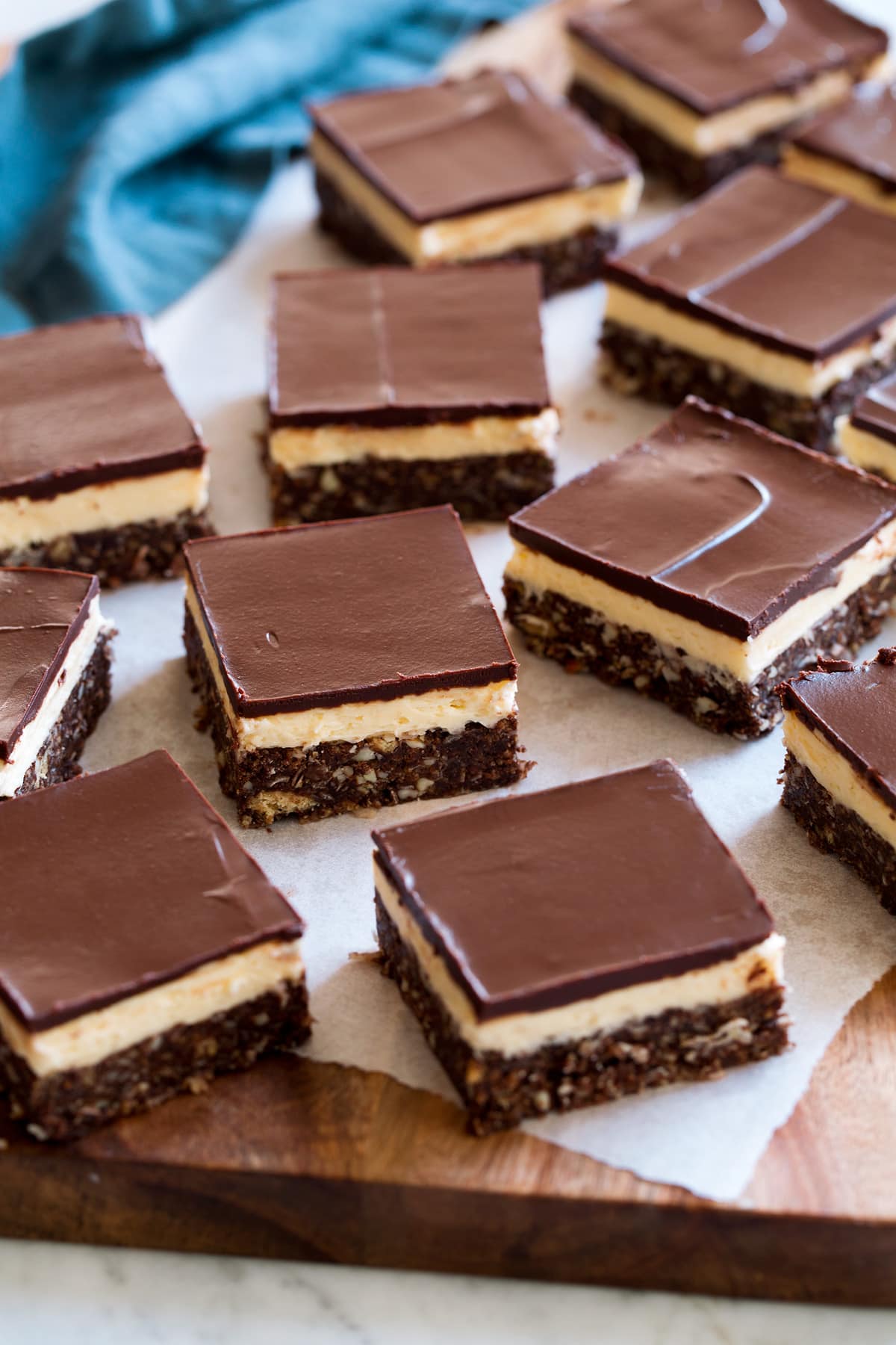 Nanaimo Bars Cut nanaimo bars laying on a piece of parchment paper set over a cutting board.