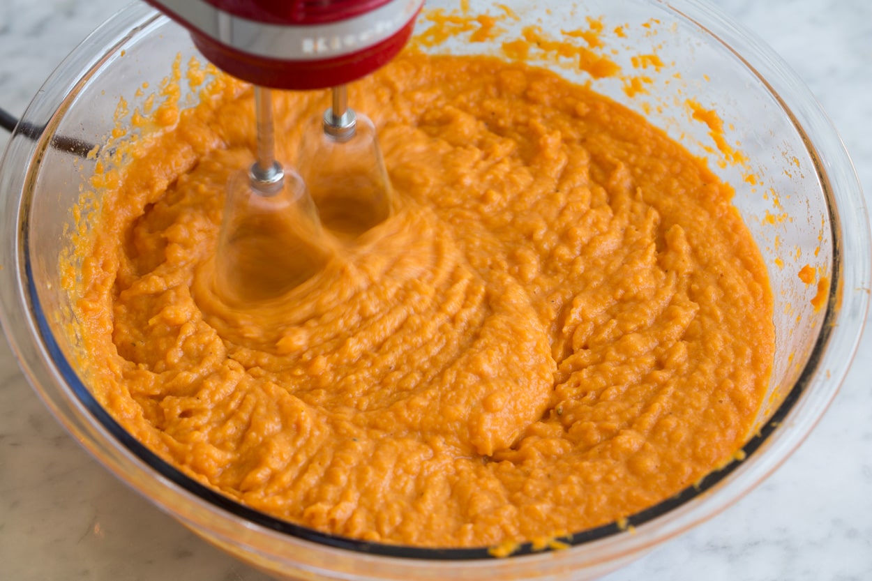 Sweet Potato Casserole Mixing sweet potato mixture in glass mixing bowl with electric hand mixer, for sweet potato casserole.