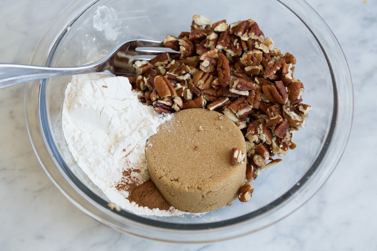 Sweet Potato Casserole Mixing pecans, flour, brown sugar in small glass mixing bowl for sweet potato casserole topping.