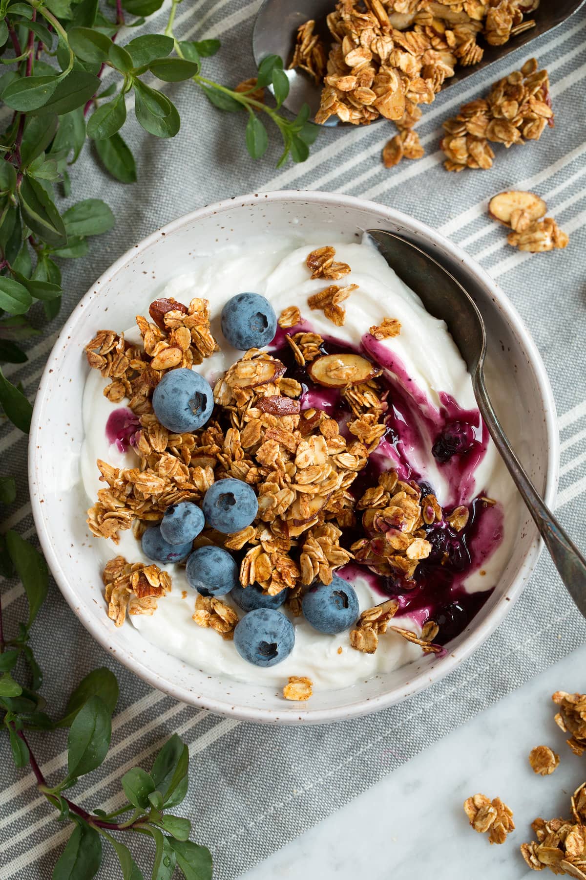 Homemade Granola Recipe Granola served over yogurt with blueberry sauce in a serving bowl.