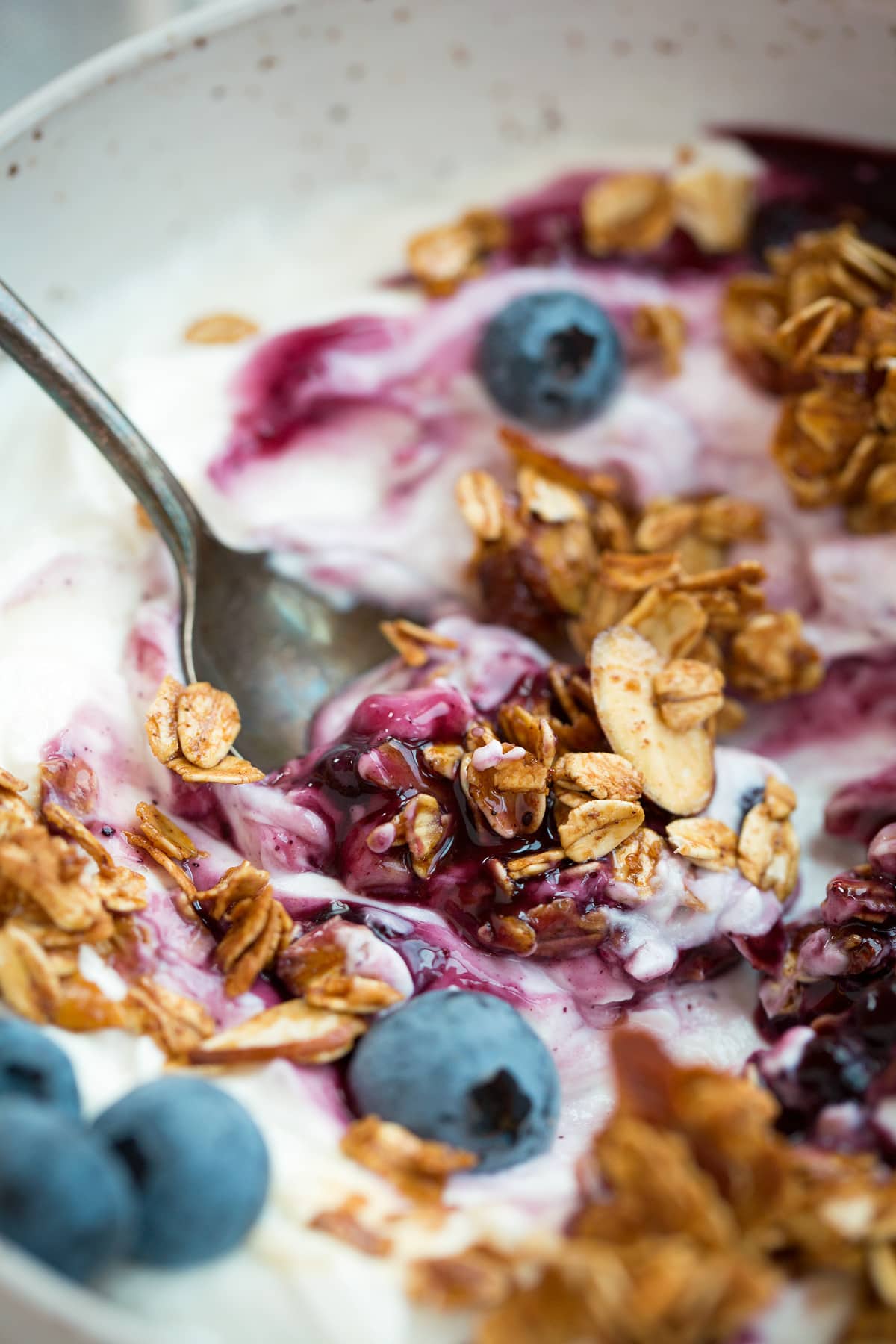 Homemade Granola Recipe Close up image of granola with yogurt, berries and blueberry sauce.