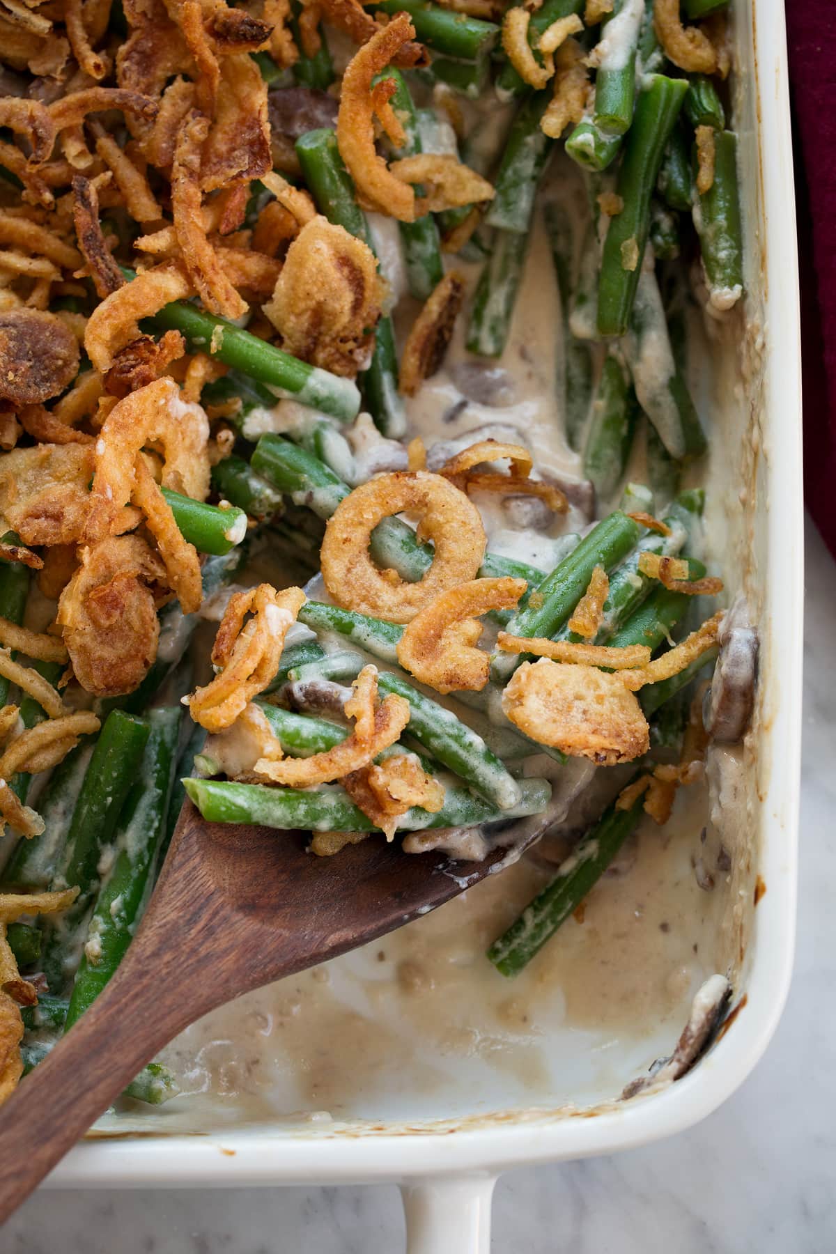 Green Bean Casserole Close up image of scoop of green bean casserole on a wooden spoon.