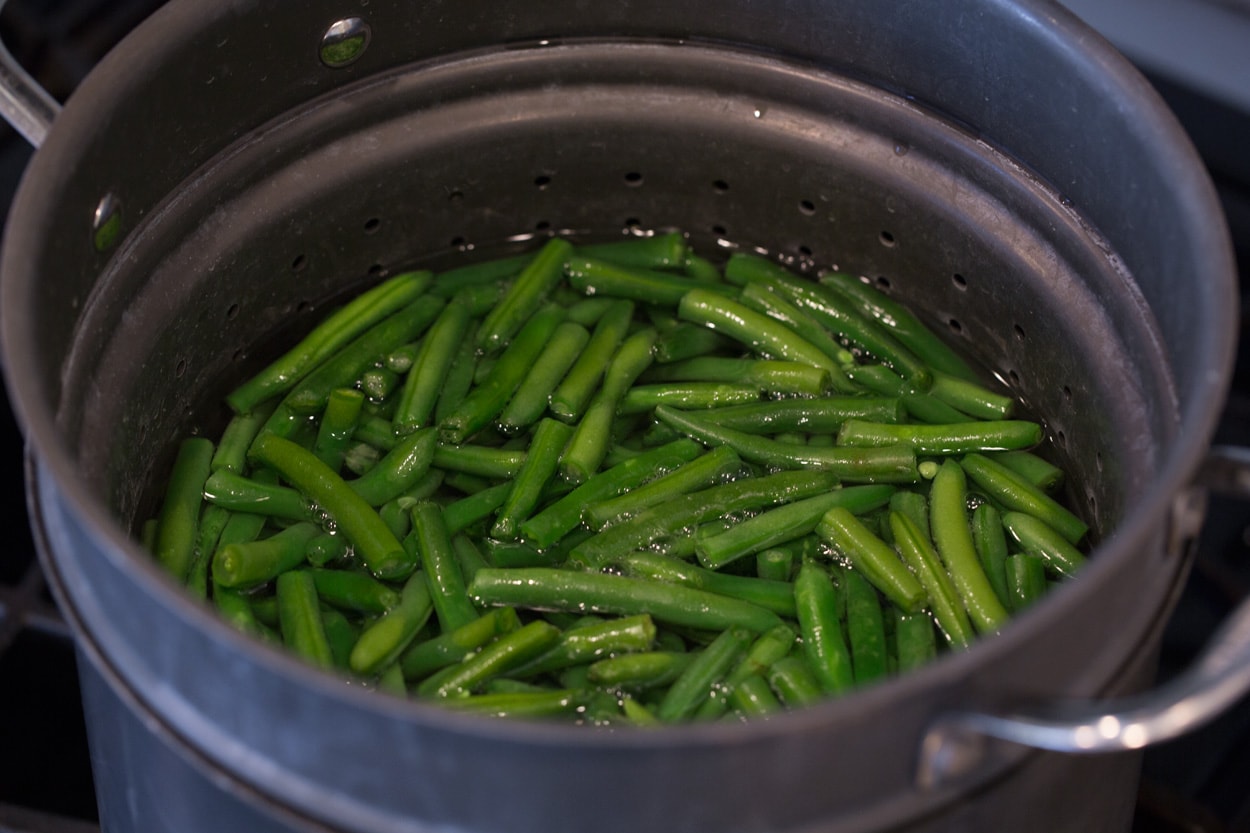 Green Bean Casserole Showing how to make green bean casserole. Start by boiling green beens in pot of water.