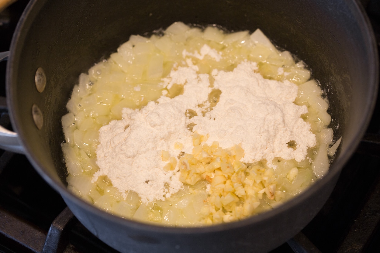 Scalloped Potatoes Showing how to make scalloped potatoes, starting with sauteing onion, garlic, and flour in butter in a medium saucepan.