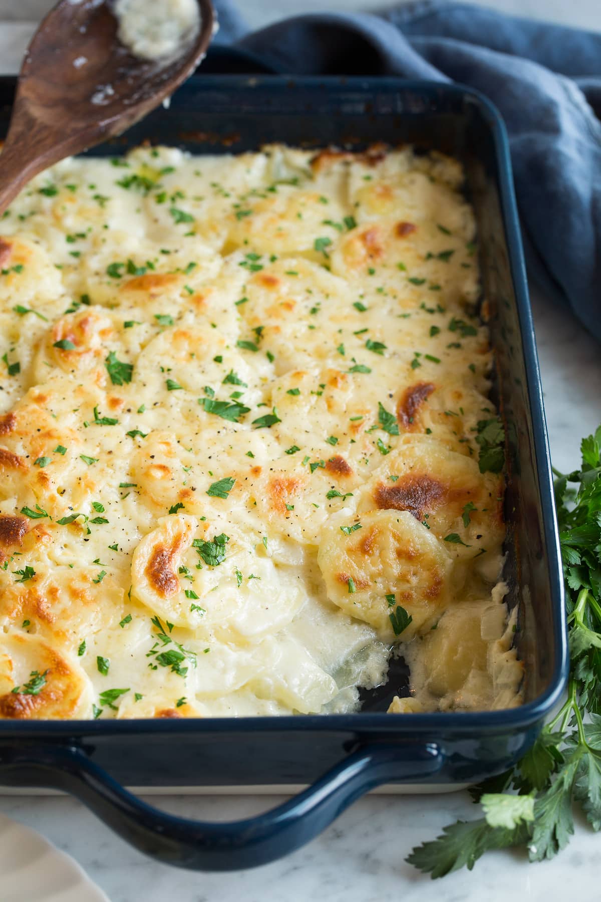 Scalloped Potatoes Scalloped Potatoes in a navy 13 by 9 inch baking dish set over a marble surface.