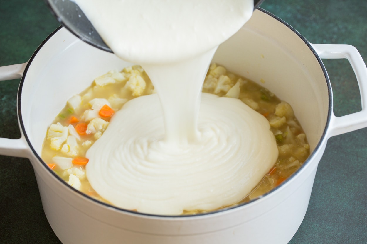 Cauliflower Soup Pouring milk mixture into Cauliflower Soup in pot.