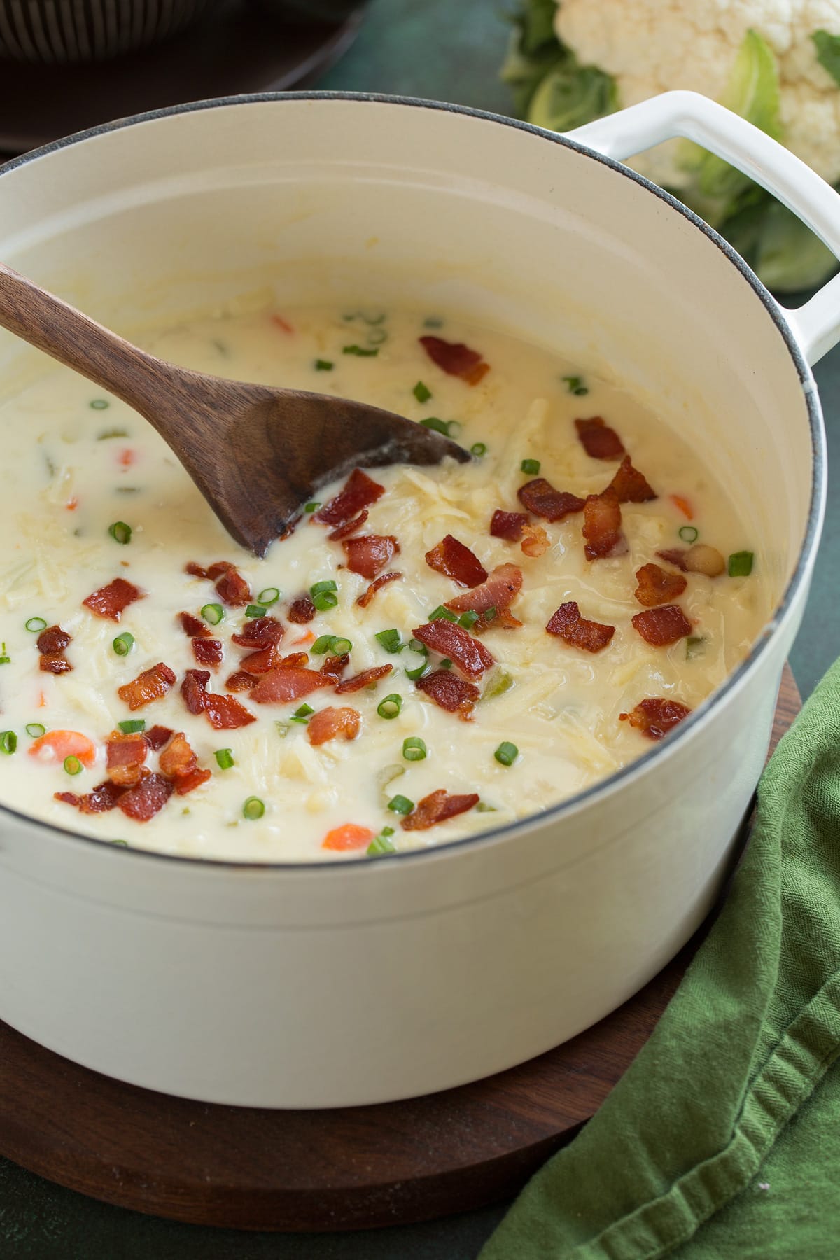 Cauliflower Soup Pot full of cauliflower soup garnished with cheddar, bacon and green onions.