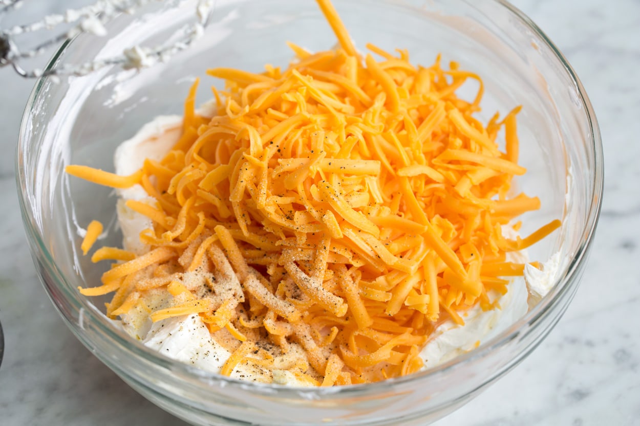 Cheese Ball Mixing shredded cheddar into cheese ball mixture.