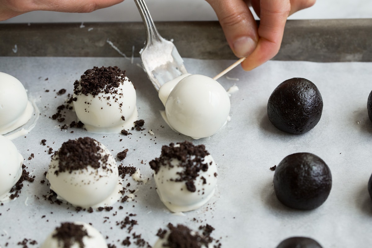How Should Oreo Truffles Be Stored? Because of the cream cheese they contain Oreo balls should be stored in the refrigerator in an are tight container. Then can sit at room temperature up to 2 hours when serving. Can They be Frozen? Yes, they can be frozen in an airtight container up to 3 months. Thaw in the refrigerator overnight. Transferring dipped oreo ball to parchment paper using a fork and toothpick.