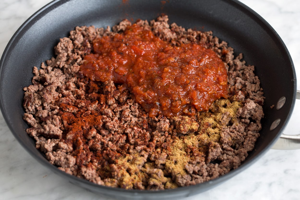 Taco Salad - so easy and flavorful! Adding salsa and spices to cooked ground beef mixture in large skillet.