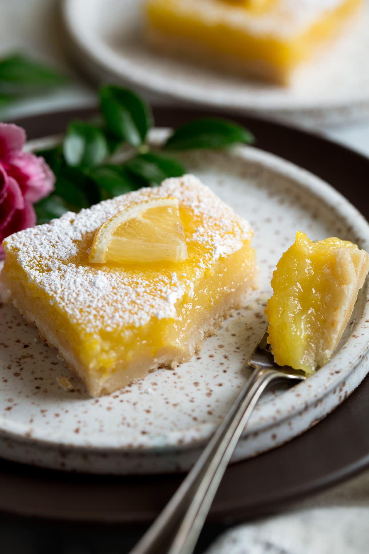 Lemon Bars Recipe Lemon bar on dessert plate with bite removed to show texture.