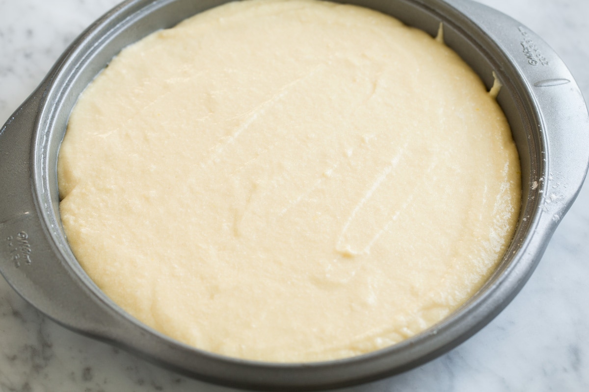 Pineapple Upside Down Cake Adding homemade cake batter over pineapple layer in cake pan.