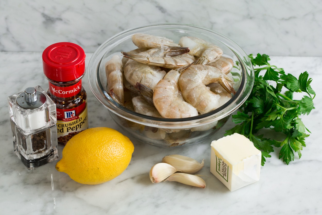 Baked Shrimp with Garlic Lemon Butter Sauce Ingredients needed to make baked shrimp shown here, including raw shrimp, butter, garlic, lemon, parsley, red pepper flakes, salt and pepper.