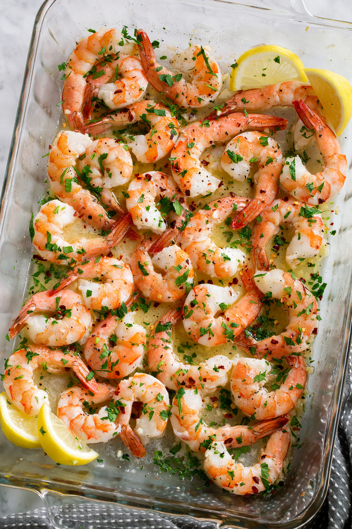 Baked Shrimp with Garlic Lemon Butter Sauce Overhead image of baked shrimp with lemon butter sauce in baking dish.