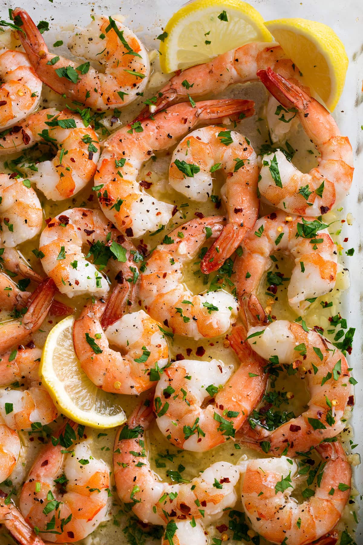 Baked Shrimp with Garlic Lemon Butter Sauce Close up image of baked shrimp in baking dish.