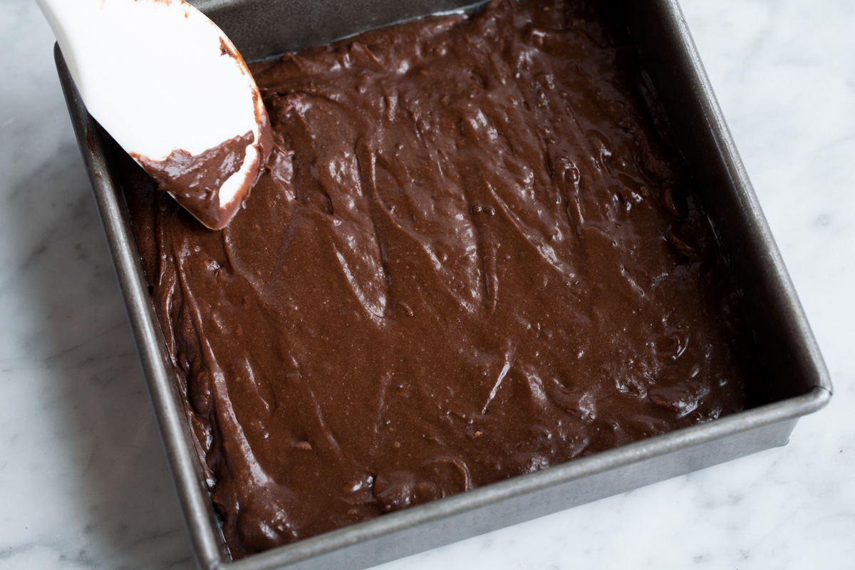 Best Cocoa Brownies Spreading brownie batter into an aluminum 8 by 8-inch baking dish.