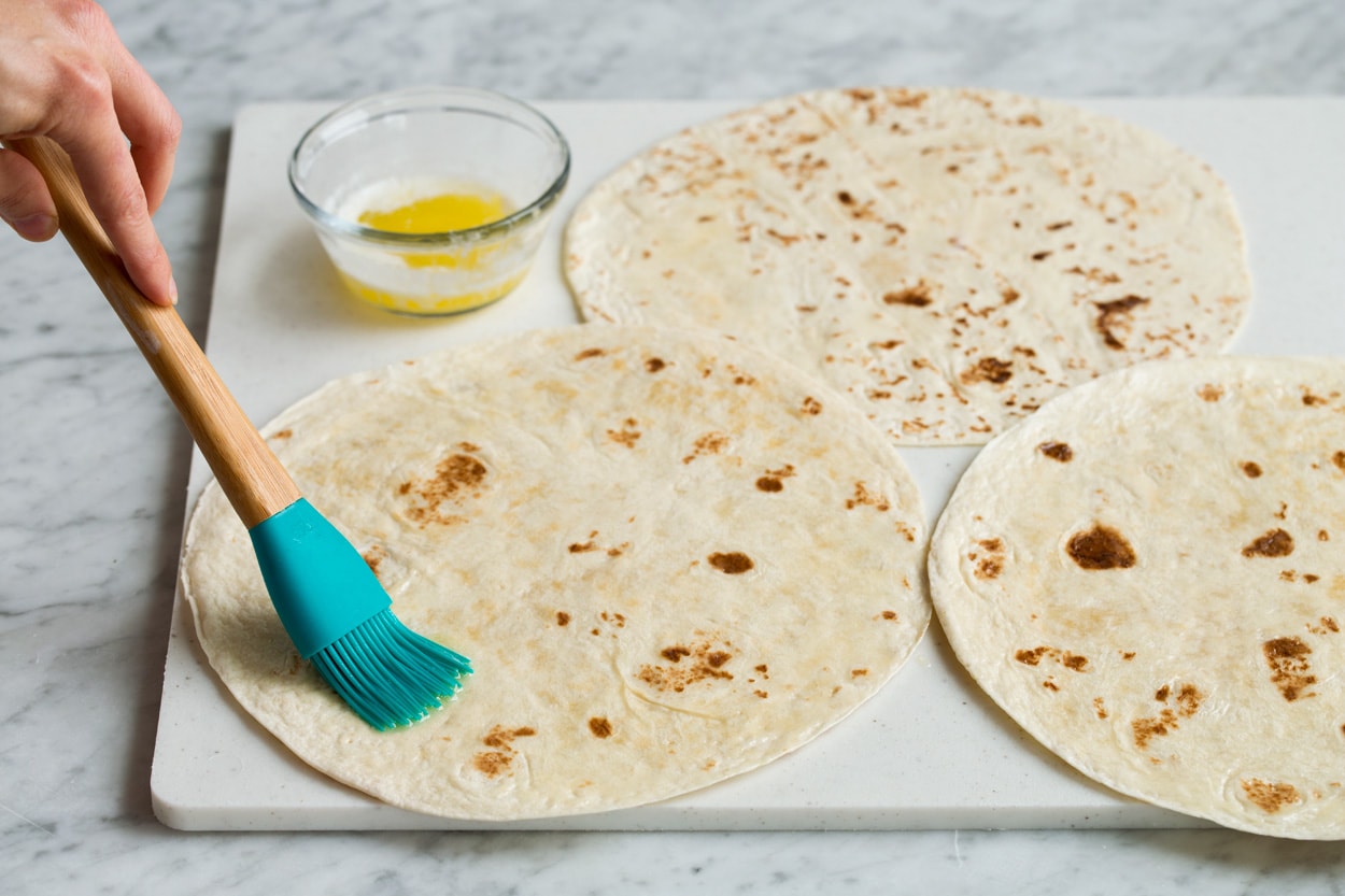 Loaded Chicken Quesadillas Brushing tortillas with melted butter to make quesadillas.