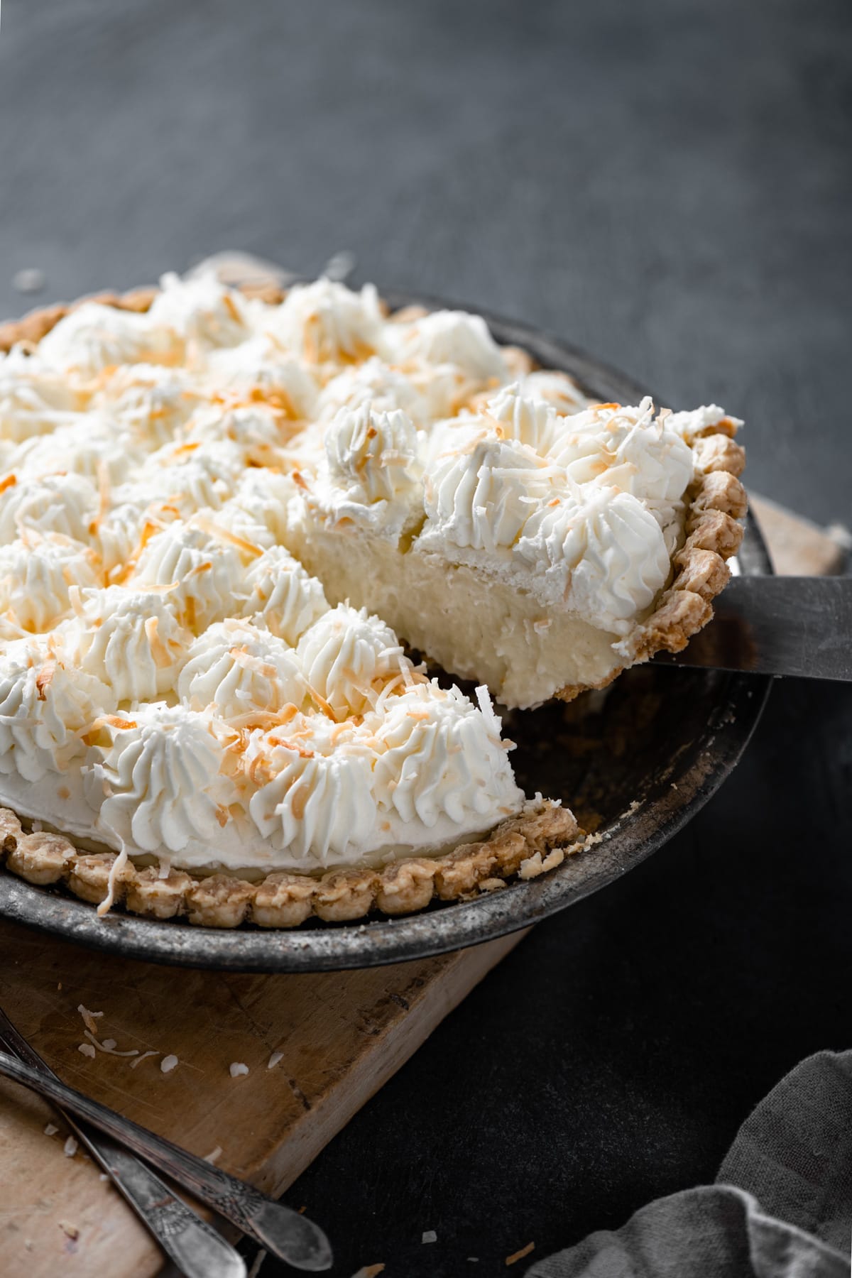Coconut Cream Pie Removing a slice of coconut cream pie from the whole coconut cream pie in pie dish.