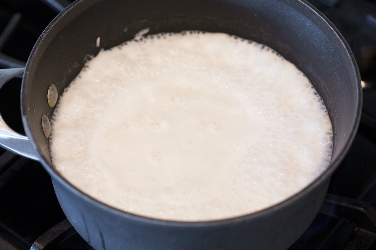 Coconut Rice Recipe Bringing coconut milk and rice mixture to a boil in saucepan over stovetop.