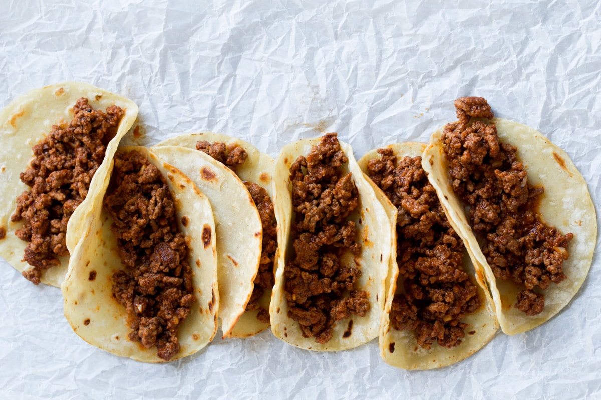 Ground Beef Tacos Row of tacos with taco filling.