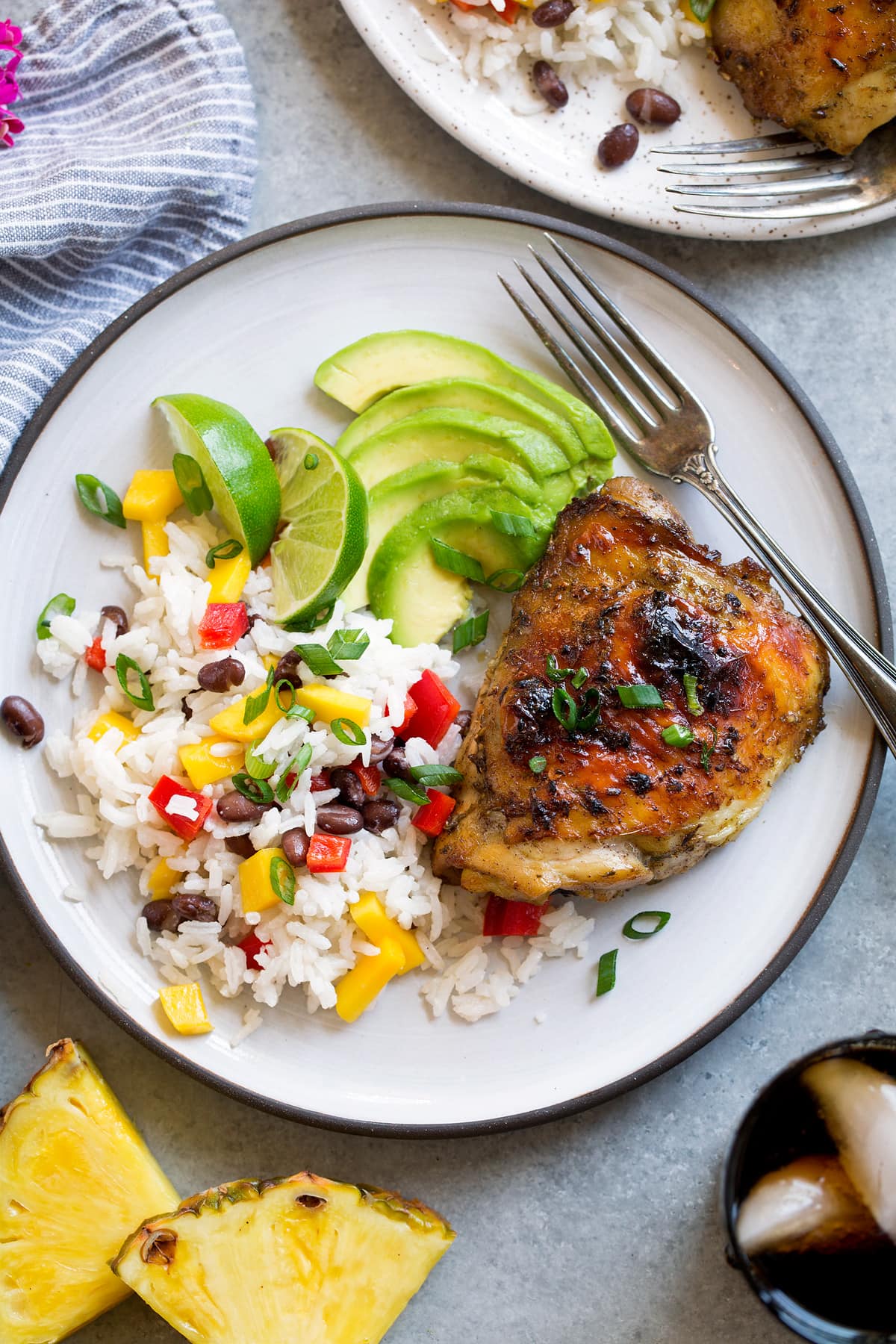 Jerk Chicken (Roasted or Grilled) Single piece of jerk chicken with a side of coconut rice and avocado.