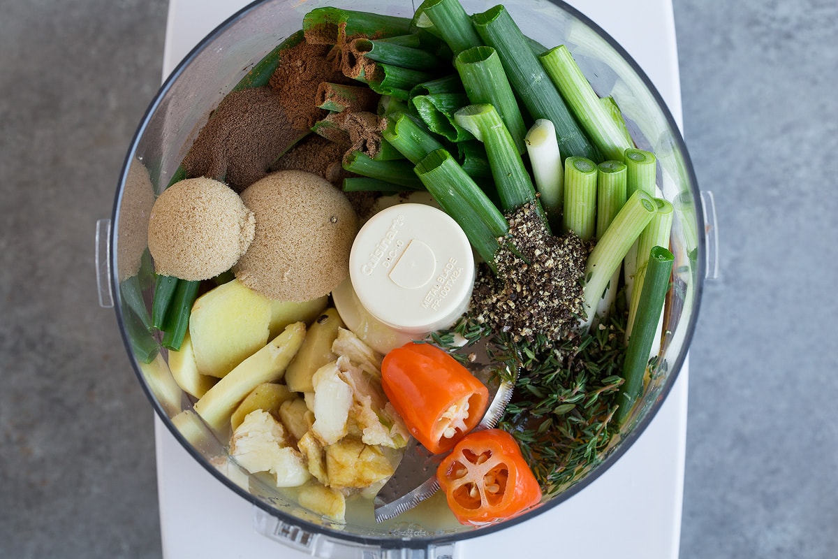 Perfect Jerk Chicken Making jerk chicken marinade. Adding ingredients to food processor including green onions, spices, pepepr, ginger, brown sugar, garlic and thyme.