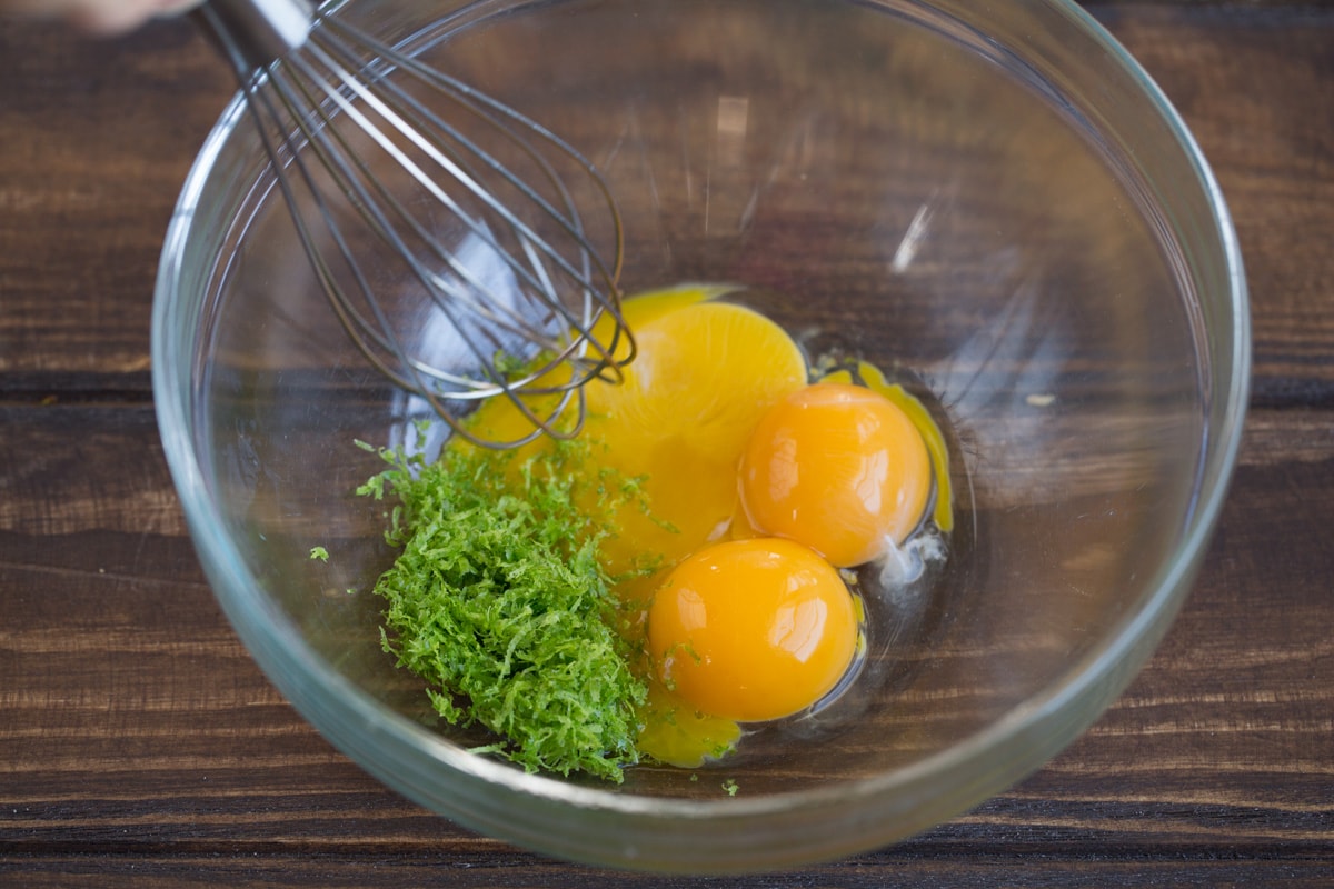 BEST EVER Key Lime Pie recipe! Showing how to make key lime pie filling. Whisking egg yolks and lime zest in a glass mixing bowl.