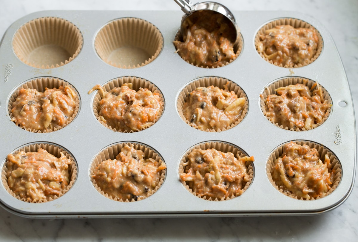 Morning Glory Muffins Scooping morning glory muffin batter into a paper lined muffin pan.