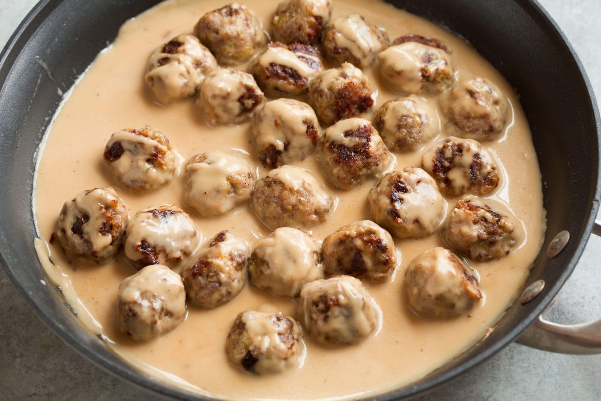 Best Swedish Meatballs (Oven Baked)! Tossing baked Swedish meatballs with sauce in skillet.