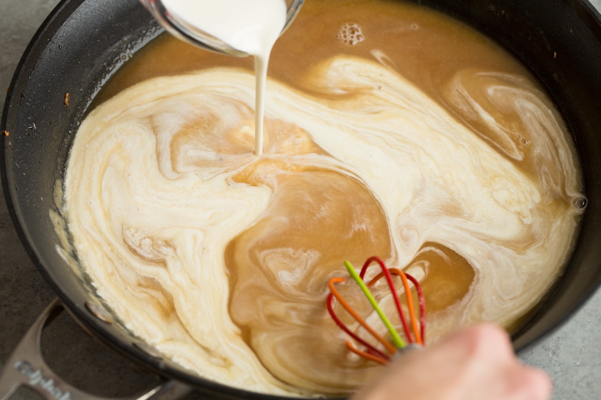 BEST Swedish Meatballs Recipe (Oven Baked)! Adding beef broth and cream to skillet to make Swedish meatball gravy.