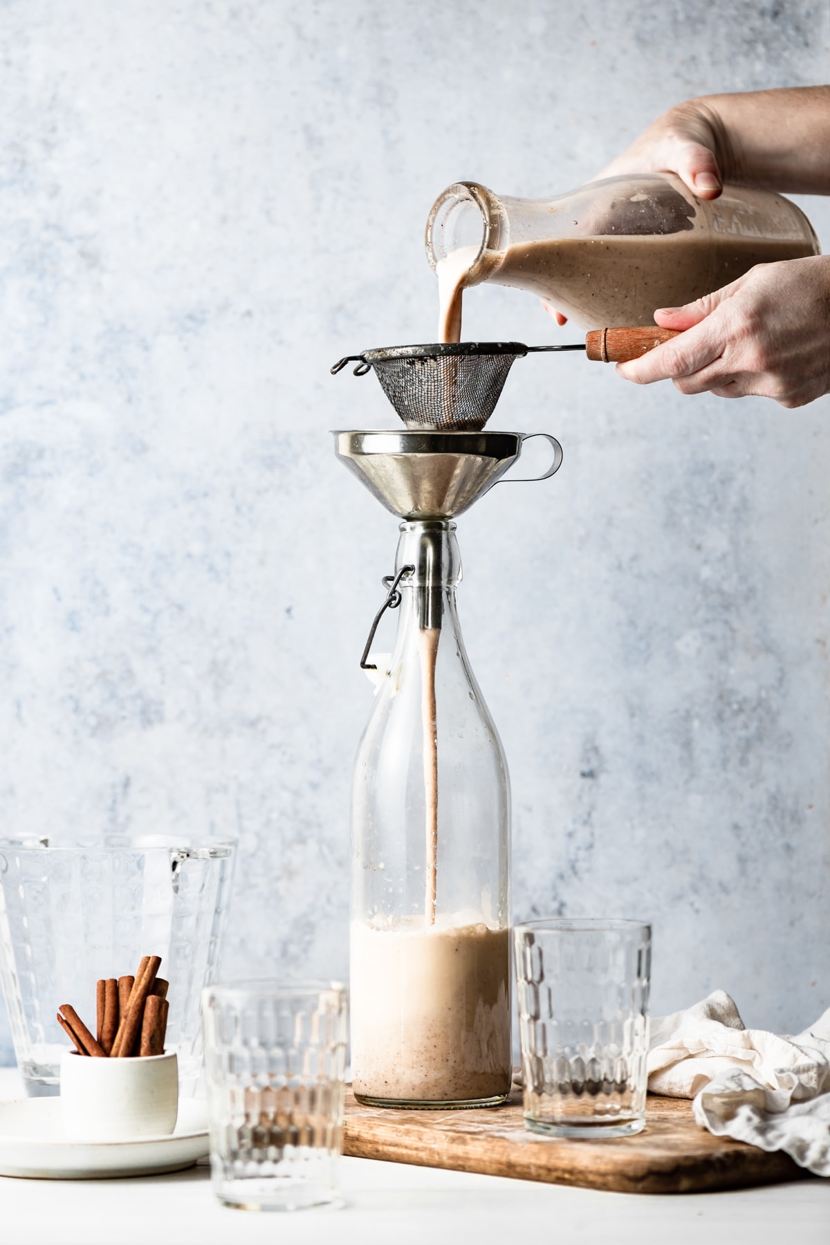 Horchata Showing how to make horchata, pouring blended mixture through a fine mesh sieve into a pitcher.