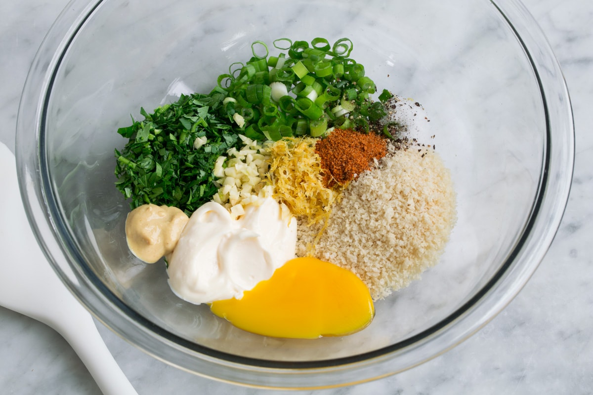 Crispy Salmon Patties (made with fresh salmon, not canned!) Showing how to make salmon patties, mixing bread crumbs, herbs, seasoning and mayonnaise in a glass mixing bowl.