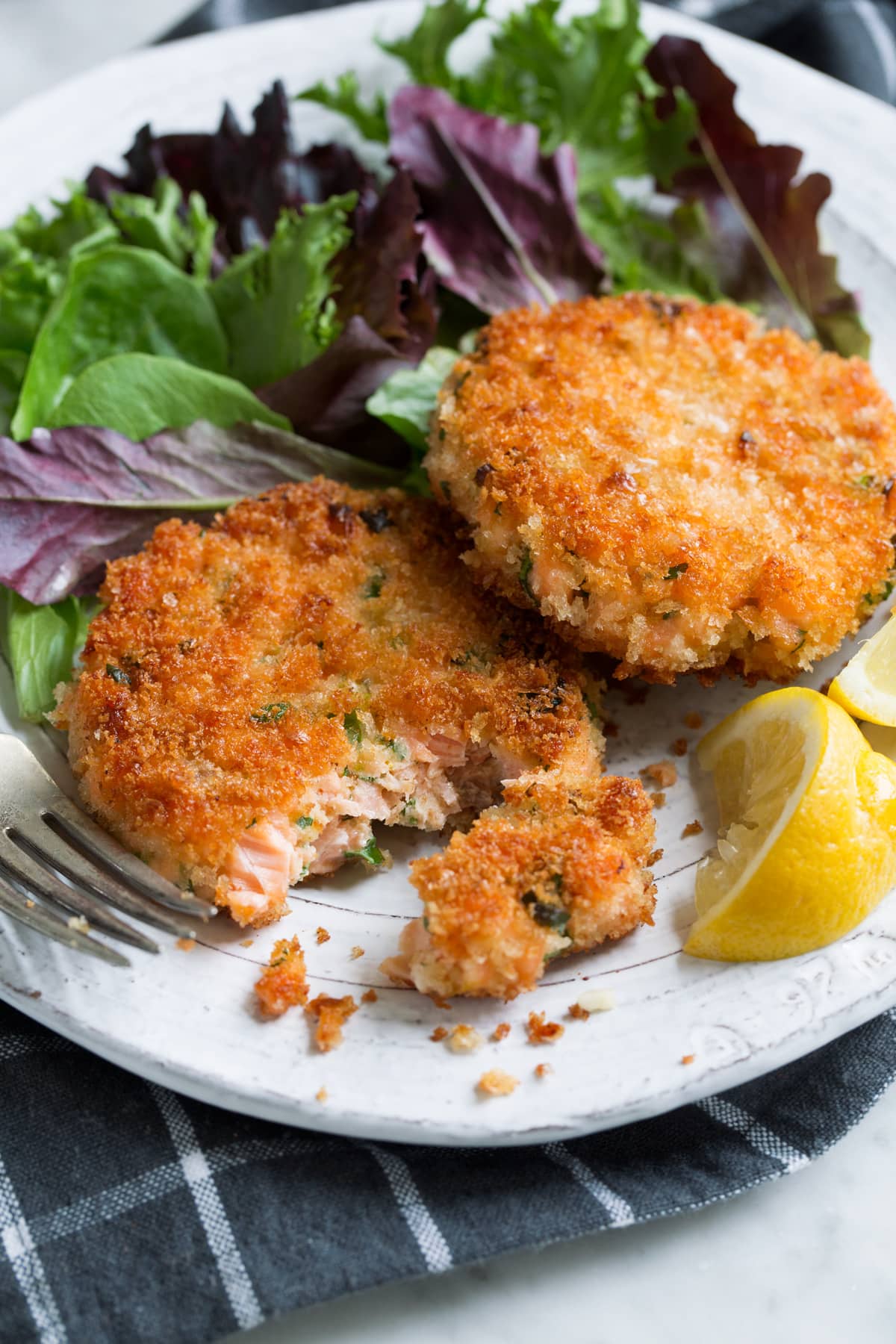 Crispy Salmon Patties (made with fresh salmon, not canned!) Two salmon patties on a white serving plate with a side of salad.