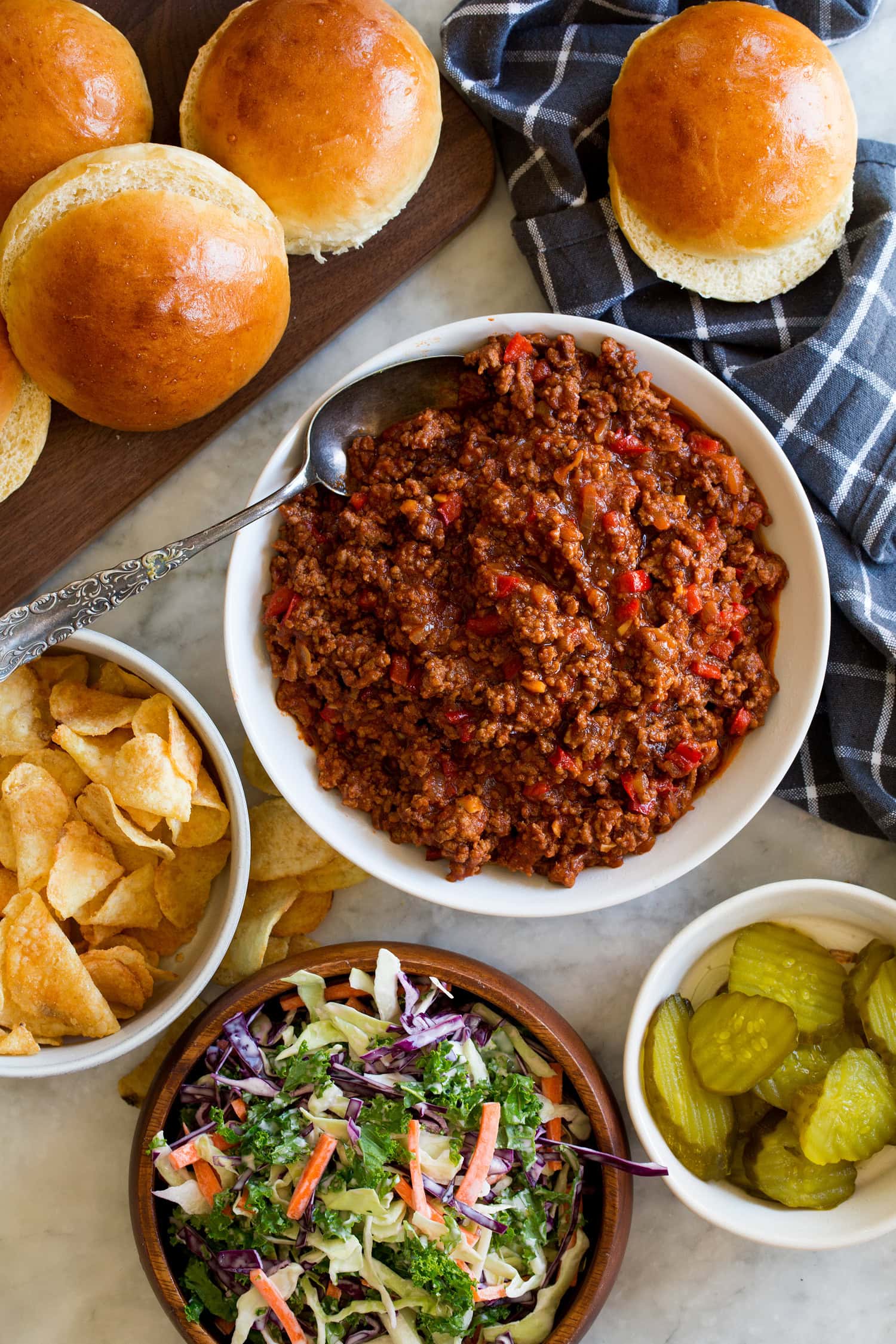 Sloppy Joes Sloppy joes filling in a bowl with buns and condiments to the side.