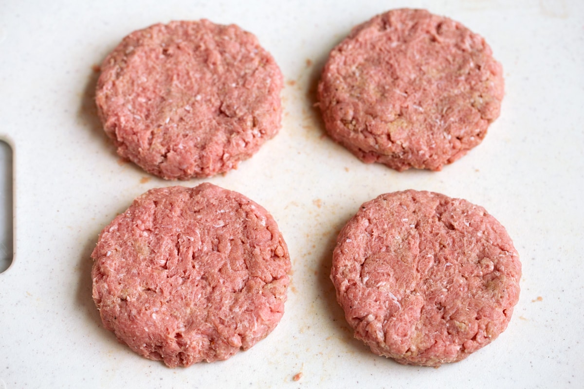 Turkey Burgers Four formed turkey burger patties on a cutting board.