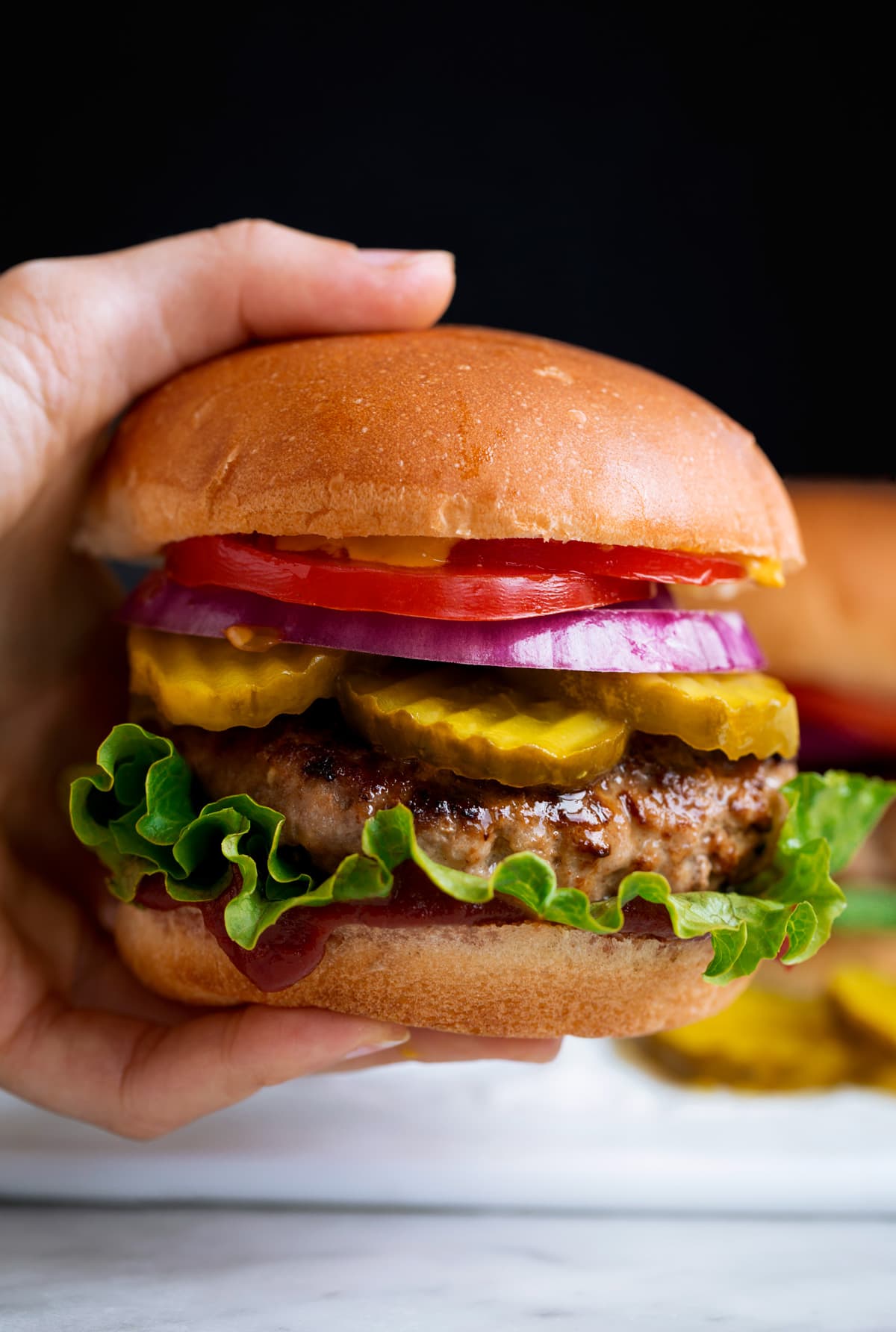 Turkey Burgers Close up image of hand holding a turkey burger on a bun.