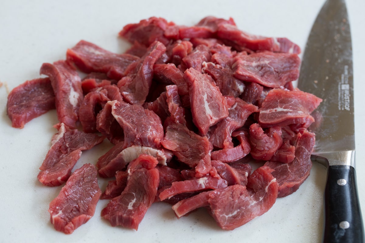 Beef and Broccoli - this is a staple dinner recipe! Easy, flavorful and sure to satisfy! #beef #broccoli #chinese #recipe Thinly sliced flank steak on a cutting board.