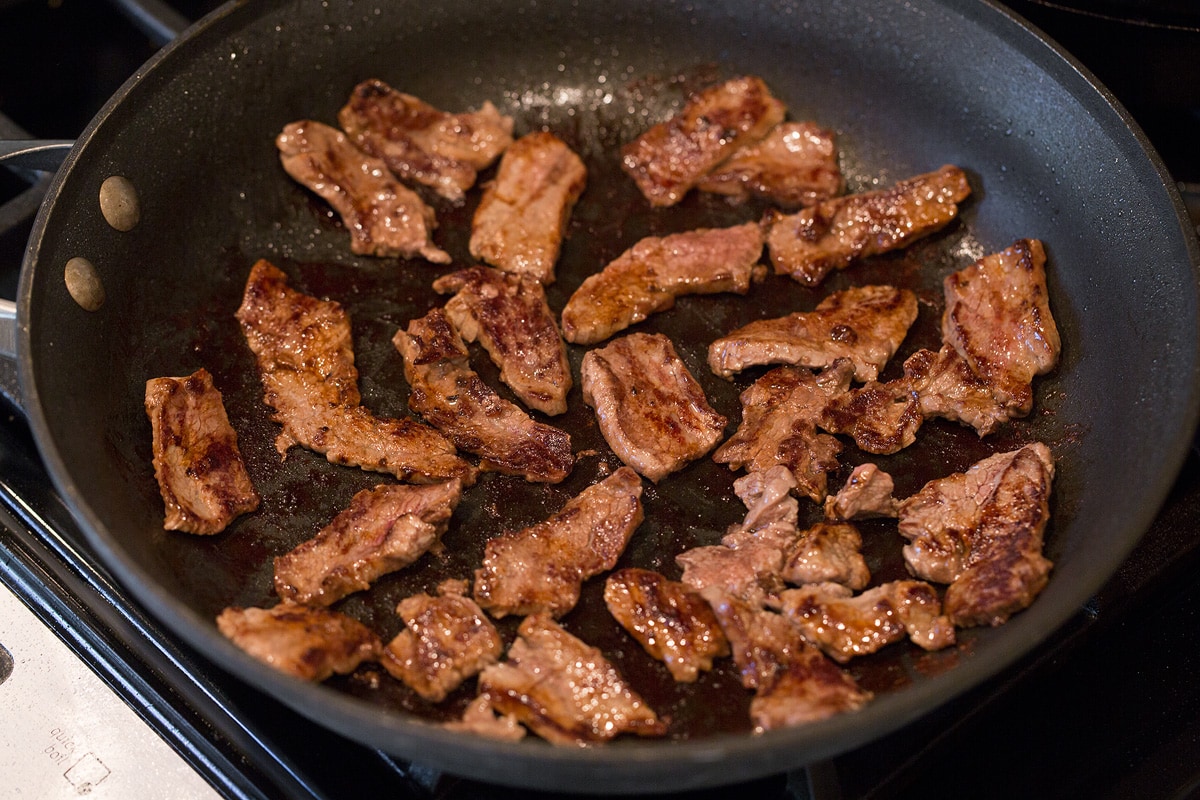 Beef and Broccoli - this is a staple dinner recipe! Easy, flavorful and sure to satisfy! #beef #broccoli #chinese #recipe Sliced steak strips cooking in a skillet.