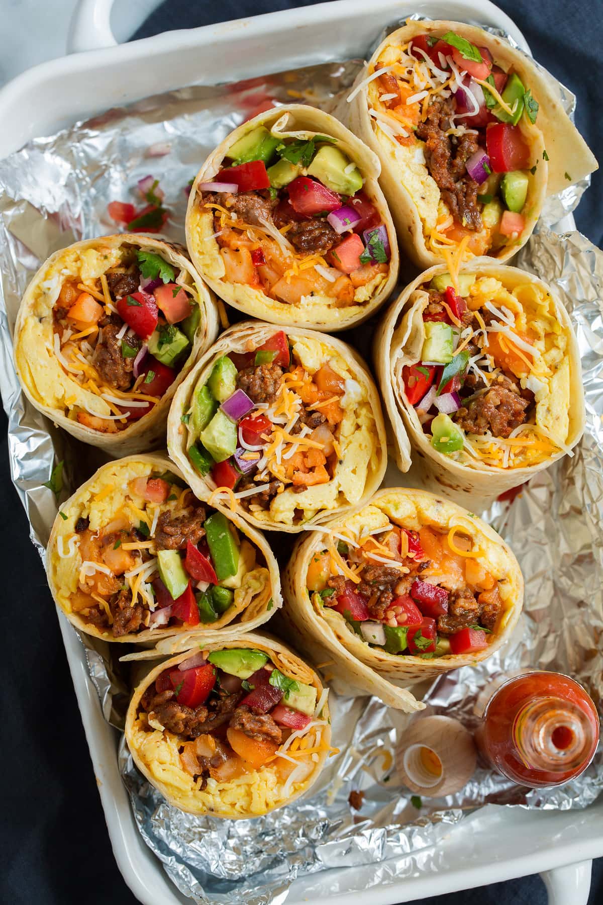 Breakfast Burritos Overhead image of breakfast burritos cut in half in a serving dish lined with foil.
