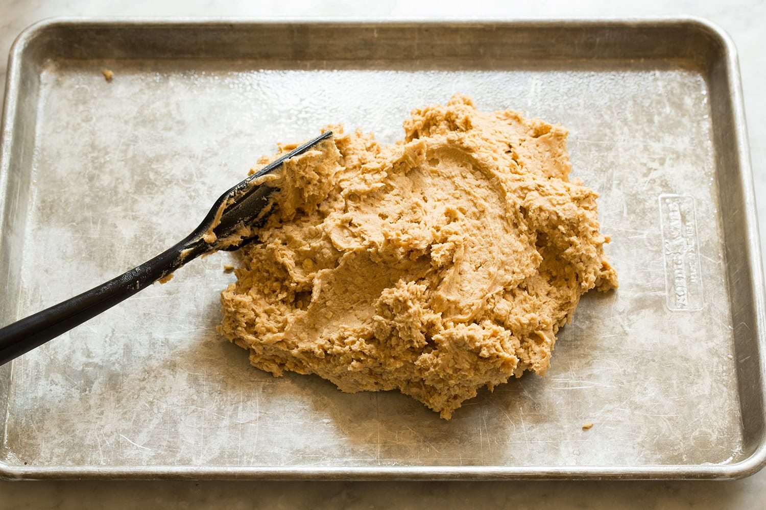 Peanut Butter Bars Completed oat peanut butter cookie dough dumped into a mound on baking sheet.