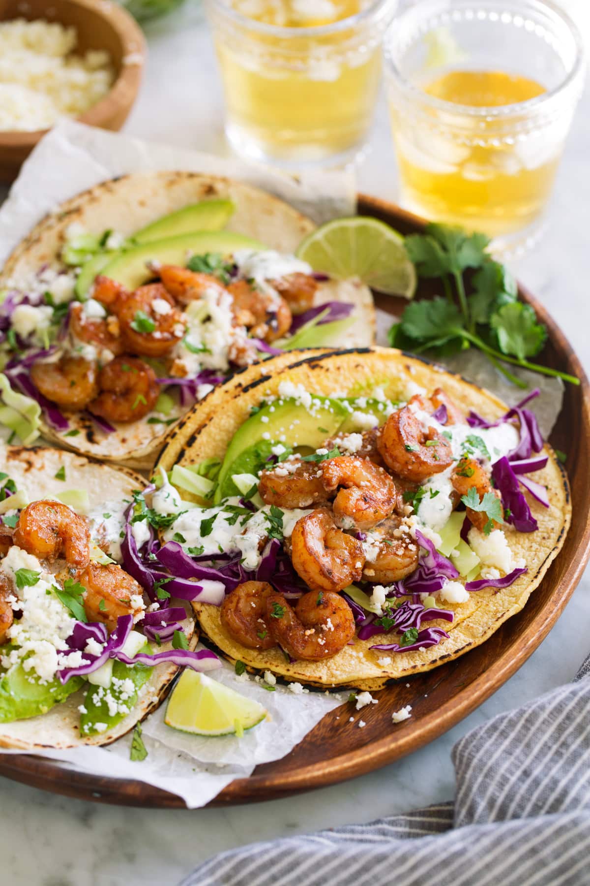 Shrimp Tacos with Cilantro Lime Crema Three shrimp tacos on a wooden platter.