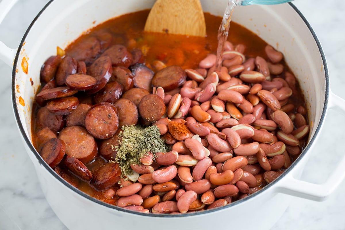 Perfect Red Beans and Rice - delicious Louisiana style comfort food at it's best! #redbeans #rice #southern #recipe #dinner Adding soaked beans, sausage and water to pot of sauteed vegetables.