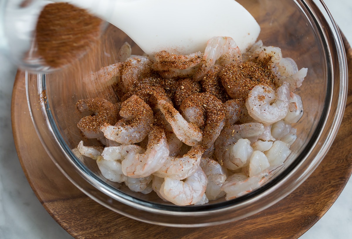 Shrimp Tacos Showing how to make Shrimp Tacos. Tossing shrimp in a glass mixing bowl with taco seasonings.
