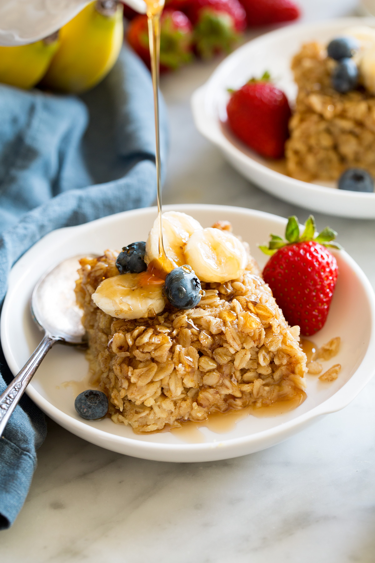 Baked Oatmeal Slice of baked oatmeal topped with fresh fruit and maple syrup.