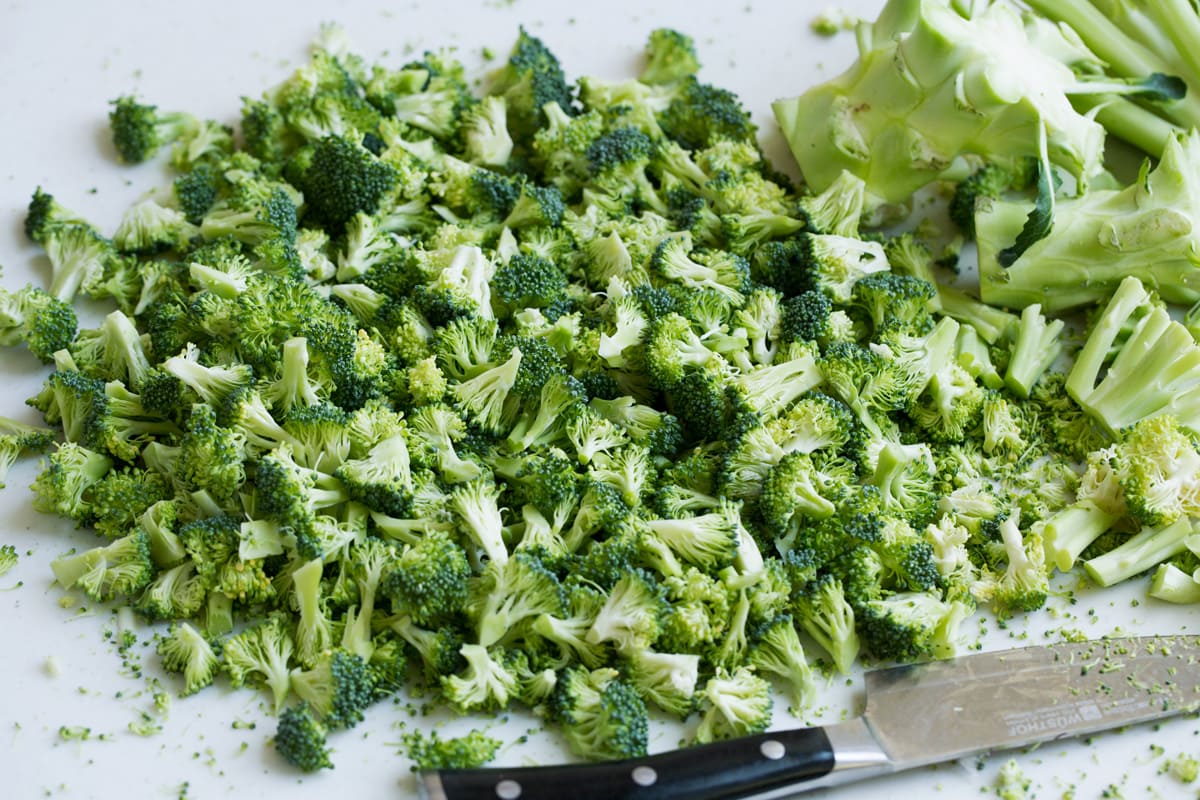 Perfect Broccoli Salad! A classic must have recipe! Made with crisp pieces of tiny broccoli florets, salty bacon, sweet dried cranberries, bright red onion, nutty toasted almonds and a creamy rich dressing. #broccoli #salad #summer #sidedish #recipe Chopping broccoli florets into tiny bits.