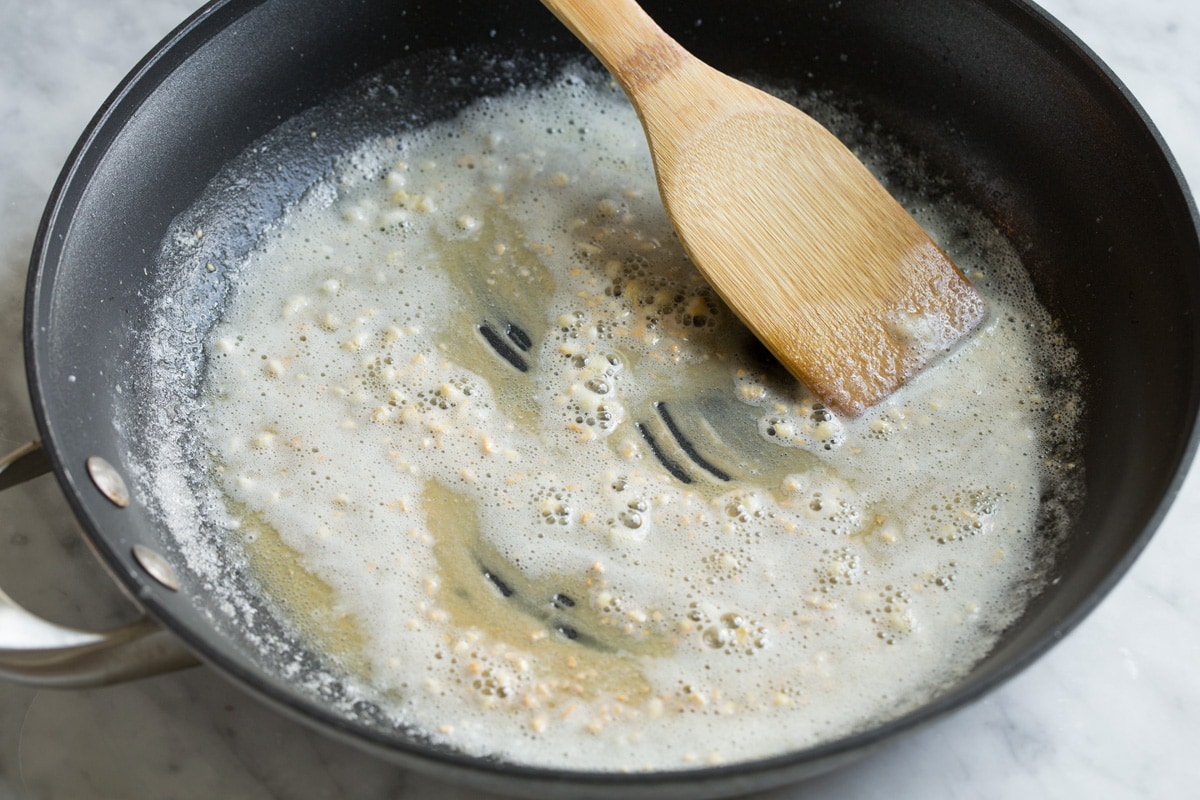 Best Alfredo Sauce - made with half milk and half cream so it's not too heavy, and includes plenty of parmesan for incredible flavor! So easy and seriously delicious! #alfredosauce #alfredo #fettuccinealfredo #dinner #pasta Sautéing flour and garlic in butter in a skillet.