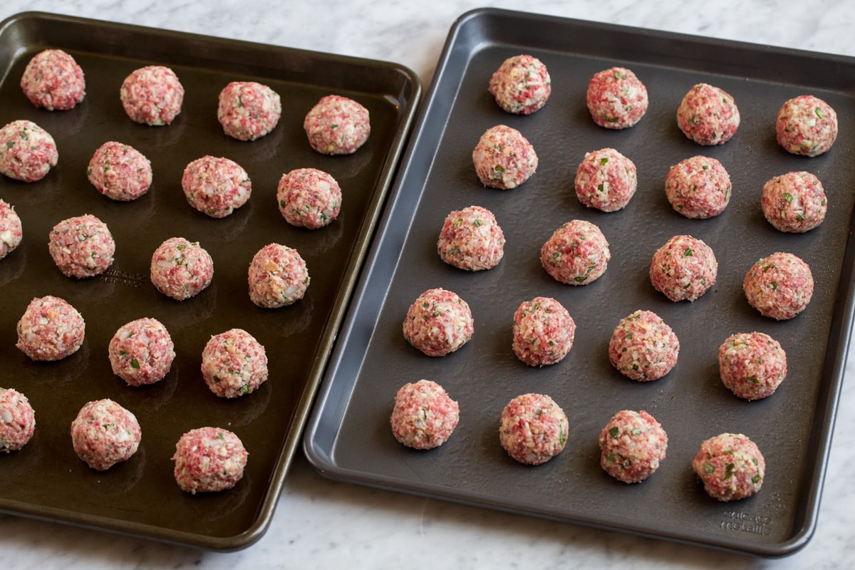 BEST MEATBALLS - these are so flavorful, so tender and packed with fresh ingredients! Makes the best spaghetti and meatballs ever! #meatballs #spaghetti #italian #dinner #groundbeef #pork #recipe Raw meatballs on two baking sheets.